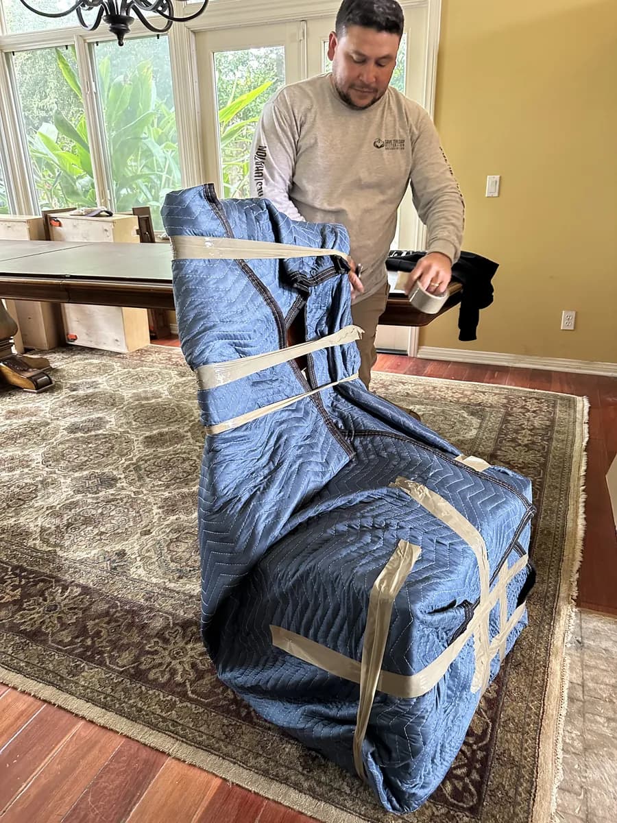 Restoration technician wrapping furniture in moving blankets during a contents pack-out