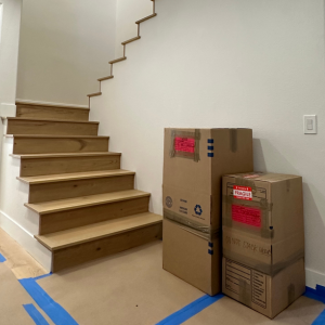 LA & OC Content Pack-Out, Cardboard boxes with 'fragile' warning stickers placed near wooden stairs, indicating careful handling.