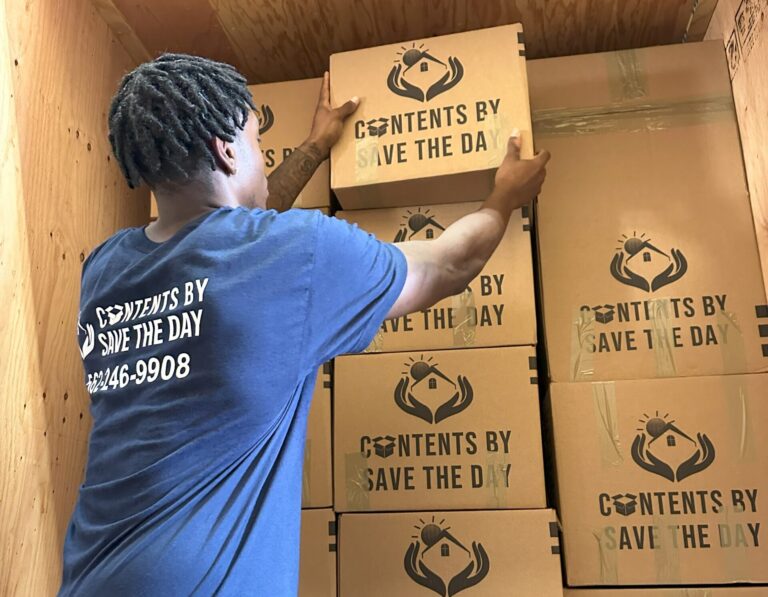 Technician from Contents by Save The Day carefully stacking branded boxes in a wooden storage unit. Have any Contents Restoration FAQ? Contact Us Today!