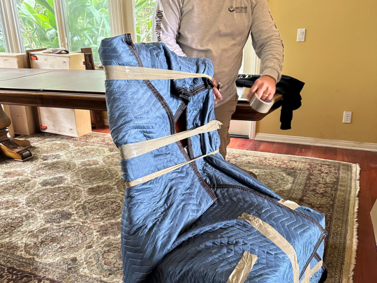 Furniture wrapped in moving blankets and secured with tape during pack-out process